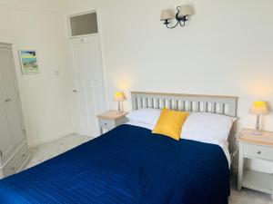 a bedroom with a bed with a blue blanket and two tables at High Tides in Lyme Regis
