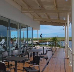 un restaurante con mesas y sillas y vistas al agua en Paz y Armonía: Con Playa Privada en Hernandarias