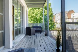 an outdoor deck with a couch and chairs on a balcony at My Stay Brussels - Couronne in Brussels