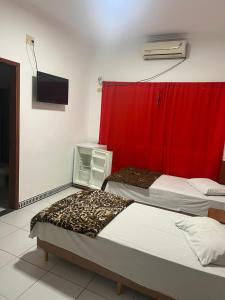 twee bedden in een kamer met een rood gordijn bij Versatile Park Hotel in Ponta Porã