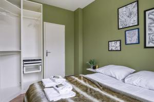 een slaapkamer met groene muren en een bed met handdoeken erop bij T2 - parking et jardin privatif in Lambersart
