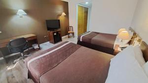 a hotel room with two beds and a television at Hotel Diego De Almagro Calama in Calama