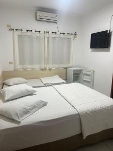 a bedroom with two beds and a flat screen tv at Versatile Park Hotel in Ponta Porã