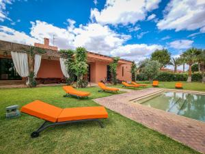 un patio trasero con sillas naranjas y una piscina en Villa de luxe service compris en Marrakech