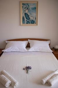 a white bed with two towels and a flower on it at Apartment Nikola Škarica 1 in Duće