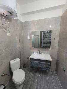 a bathroom with a toilet and a sink and a mirror at Family Oasis in Vlorë