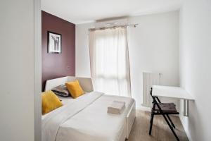 1 dormitorio con cama blanca con almohadas amarillas y escritorio en Chic apart Disneyland terrace parking en Bussy-Saint-Georges