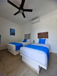 two beds in a bedroom with a ceiling fan at blue BOCANA in Santa Cruz Huatulco