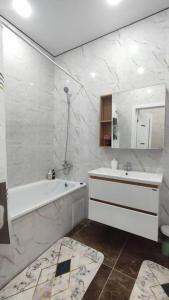 ein weißes Badezimmer mit einer Badewanne und einem Waschbecken in der Unterkunft Люкс апартаменты в ЖК Shanyrak in Pawlodar