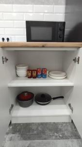 a shelf with dishes and a microwave in a kitchen at Люкс апартаменты в ЖК Shanyrak in Pavlodar