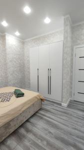 a bedroom with a bed and white cabinets at Люкс апартаменты в ЖК Shanyrak in Pavlodar