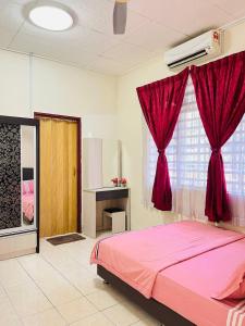 a bedroom with a pink bed and a red curtain at Sofea Homestay Ipoh in Ipoh