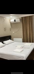 a bed with two white towels on top of it at Hotel Mariana in Kutaisi