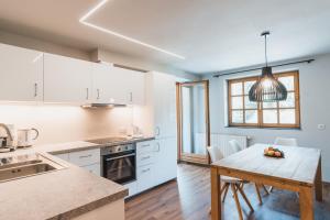 a kitchen with white cabinets and a wooden table at Felbermayer Appartements in Gaschurn