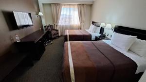 Habitación de hotel con 2 camas y escritorio en Hotel Diego de Almagro Alto el Loa Calama, en Calama