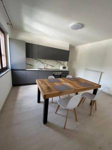 uma cozinha com uma mesa de madeira e cadeiras brancas em Appartamento Alpi Retiche em Morbegno