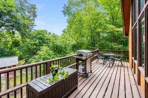 a wooden deck with a grill and a table at Quaint Loft Cabin w Hot Tub, FirePit, Deck & Grill in Hedgesville