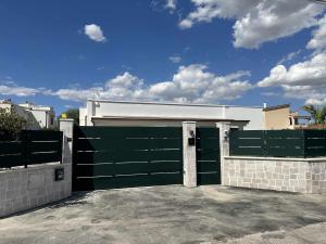 un garage avec une porte de garage verte et une clôture dans l'établissement Casa del Sol Luxury Estate Puglia, à Leporano Marina