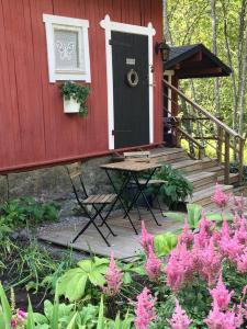 a red house with a black door and a table and pink flowers at Savikulma B&B in Mynämäki