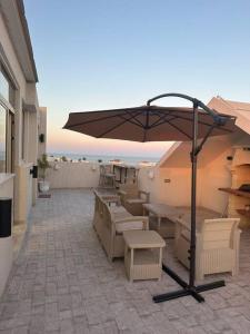 eine Terrasse mit einem Sonnenschirm, Tischen und Stühlen in der Unterkunft Luxury Rooftop WiFi, AC, BBQ in Rejiche