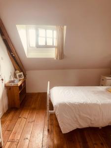 1 dormitorio con cama, ventana y suelo de madera en Trevejean chambre d'hotes de charme, en Guerlédan