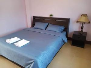 um quarto com uma cama azul com duas toalhas em หม่อนเมือง รีสอร์ท em Chiang Rai