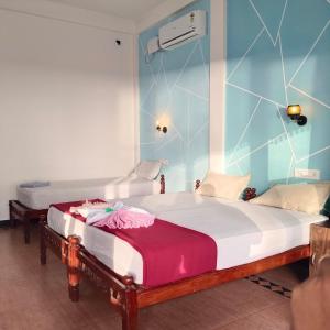 - 2 lits dans une chambre aux murs bleus dans l'établissement Cherai Ocean View Home, à Cherai Beach