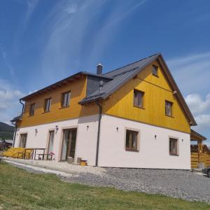 een groot wit en geel huis met een gambrel dak bij Chalupa 66 - Bukovka in Červená Voda