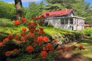 a house on a hill with flowers in front of it at Cozy Lakefront with Beach of your own! in Franklin