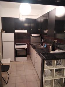 a kitchen with black cabinets and white appliances at Glyfada First Center in Athens