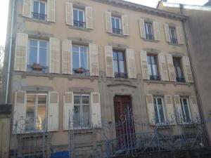 a building with shuttered windows and a red door at Studio Plaisance in Contrexéville