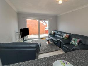 a living room with a black leather couch and a television at 10 Southcliffe Drive in Filey