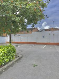 een parkeerplaats met een boom en een witte muur bij Monkbridge Mews Apartment in York