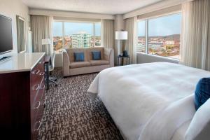 Cette chambre comprend un grand lit, une chaise et une fenêtre. dans l'établissement Marriott Philadelphia West, à West Conshohocken