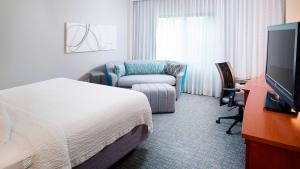 una camera d'albergo con letto e sedia di Courtyard by Marriott Roanoke Airport a Roanoke