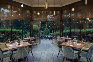 Delta Hotels by Marriott Swindon في سويندون: مطعم بطاولات وكراسي ونوافذ كبيرة