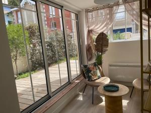 a room with large windows and a chair and a table at La Villa Mandarine sur Arcachon in Arcachon