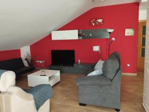 a living room with red walls and two couches and a tv at Ático Vista Alegre in Lerma