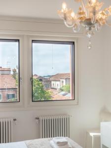 1 dormitorio con 2 ventanas y lámpara de araña en Le Terrazze en Venecia