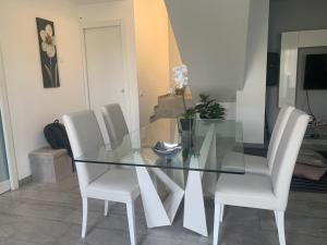 una mesa de comedor de cristal y sillas blancas en una habitación en Casa in affitto, en Ragalna