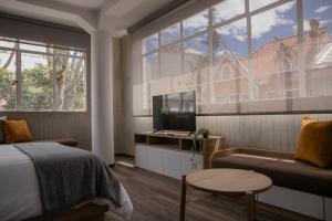 - une chambre avec un lit, une télévision et un canapé dans l'établissement 5Q House Quinta Camacho, à Bogotá