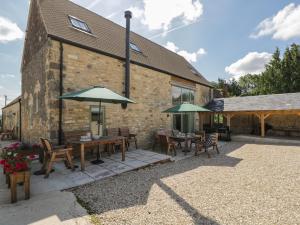 a patio with tables and umbrellas in front of a building at The Old Barn in Witney