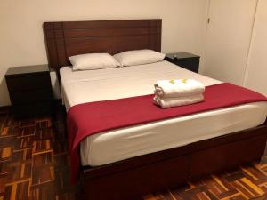 a bed with a red blanket and two towels on it at NEW INKAWASI ( COZY HOUSE) in Lima