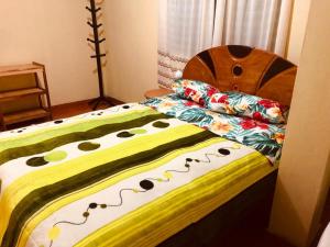 Una cama con una manta colorida y almohadas. en Habitación simple, en Urubamba