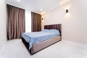 a bedroom with a bed with a blue comforter at 2-Bedroom Family Grandeur Apartment in Chişinău