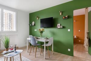 聖艾蒂安的住宿－APPART COSY - COMME À LA MAISON - ST ETIENNE，一间拥有绿色墙壁和桌椅的用餐室