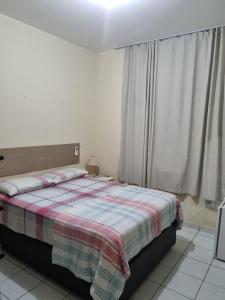 1 dormitorio con 1 cama con manta y ventana en Sua casa fora de casa en João Pessoa