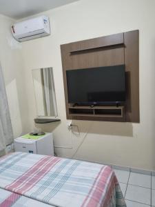 1 dormitorio con TV de pantalla plana en la pared en Sua casa fora de casa, en João Pessoa