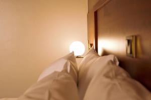 a bed with white pillows and a light on it at Blueberries Hotel in Entebbe