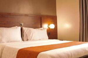 1 dormitorio con 1 cama grande con sábanas y almohadas blancas en Blueberries Hotel, en Entebbe